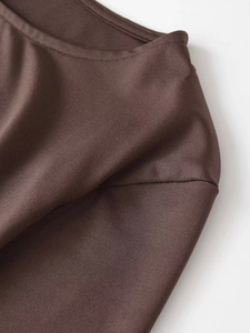 Close-up of reinforced double-stitching detail on a dark brown ribbed knit top