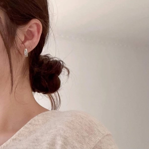 Close-up of minimalist silver V-shaped stud earring worn on the earlobe