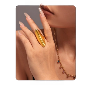 Detail of a wide gold-plated irregular ring with mirror finish and colorful gemstone necklace