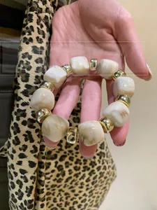 Detail of acrylic marble bead bracelet with gold metal spacers on model's wrist