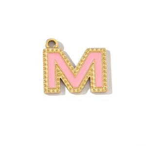 Macro view of a gold-plated letter M pendant featuring pink enamel and beaded edge texture
