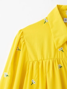 Detail of yellow French floral embroidery on shirt collar with puff sleeve texture