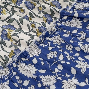 Floral patchwork dress fabric detail with white and blue daisy patterns and stitching