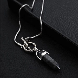 Close-up of black hexagonal pillar pendant with silver snake chain on display