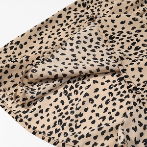 Detailed view of leopard print satin fabric with fine hem stitching on a mini dress