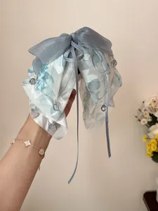 Close-up of sea salt blue ribbon hair claw with floral organza and crystal bead detail