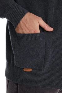 Detail of knit cardigan side pocket with brown leather brand tag on dark gray fabric