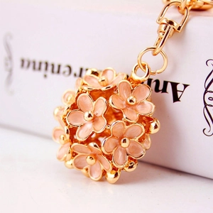 Detail of rose gold metal floral sphere keychain with enamel flowers on book