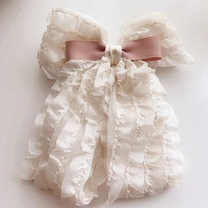 Close-up of layered white chiffon bow hair clip with a pink satin ribbon center