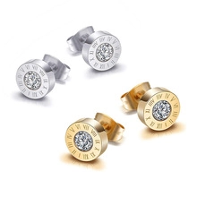 Macro shot of silver and gold stainless steel earrings with roman numerals and zircon