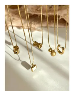 Detail of assorted gold snake chain necklaces with geometric pendants on white background
