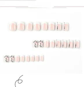 Detail view of short press-on nails with white French tips and black floral hand-painted designs