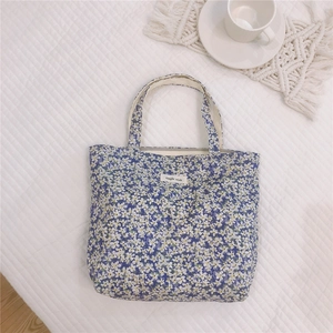 Dettaglio della borsa tote in tela a fiori blu con etichetta semplice e margherite