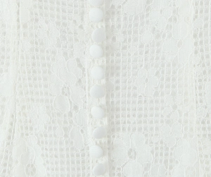 Détail de la texture dentelle florale et boutons recouverts de tissu sur robe blanche