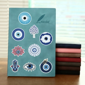 Detail of blue notebook cover featuring Evil Eye and Fatima Hand symbols with multi-color options