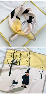 Detailed view of square silk scarf with black cat and cottage illustration in a gold frame