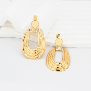 Close-up of chunky gold U-shaped earrings with vertical ribbed texture on white display
