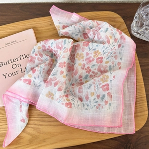 Detailed view of floral cotton linen scarf with gradient edges on wooden tray and book