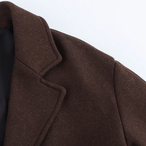 Close-up detail of dark brown wool coat showing notch lapel and fine stitching texture