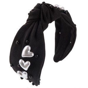 Détail du serre-tête en tissu noué avec perles noires et ornements en forme de cœur