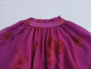 Détail d'une robe en mousseline fleurie violette avec col à volants et plis aux épaules