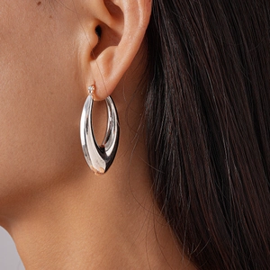 Macro detail of silver drop earrings with high-polish mirror finish on model