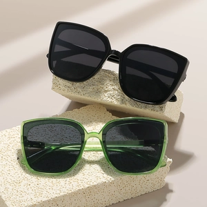 Modern oversized square sunglasses in black and transparent green on stone podium