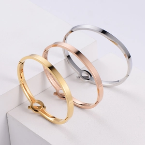 Three-color minimalist bangle bracelets in gold, silver, and rose gold on white cubes