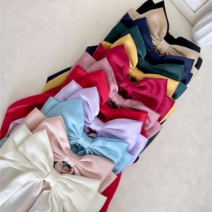 Elegant satin bow hair clips in multiple colors arranged on a neutral background