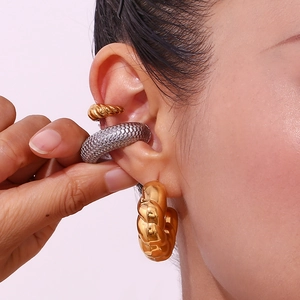 Detail of twisted gold earcuff and silver textured wide band earring on ear