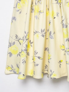 Detail of yellow rose floral print on a poplin mini dress with flowing hemline
