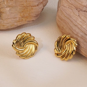 French vintage style gold spiral stud earrings displayed on natural stones