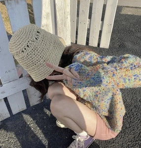 Detail of hollow woven beige straw bucket hat with colorful knit texture under sunlight