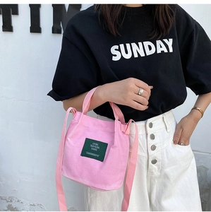 Street style shot of a pink canvas mini bucket bag worn cross-body against a clean background