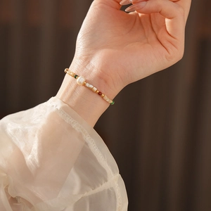 Détail d'un bracelet doré orné de perles d'eau douce et de pierres précieuses colorées