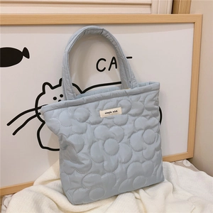 Close-up of light blue quilted handbag featuring floral stitching and simple wish label