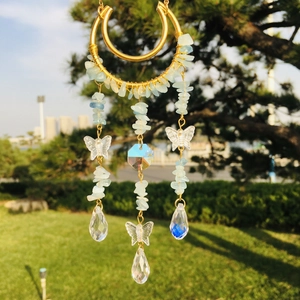 Detail of a handmade golden moon suncatcher with light blue crystals and butterfly pendant