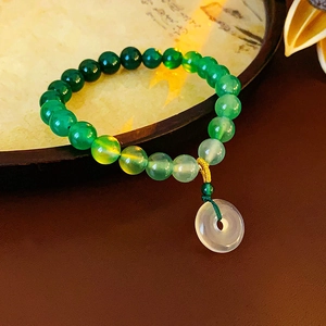 Macro detail of gradient green beads bracelet with a white jade safety buckle pendant
