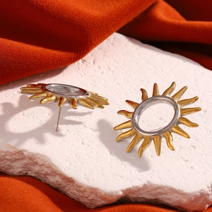 Detail of two-tone sun stud earrings in 18K gold and silver on a textured stone