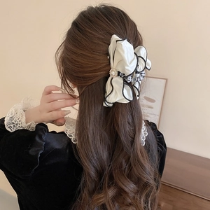 Elegant white fabric bow hair claw with pearl detail on a half-up hairstyle