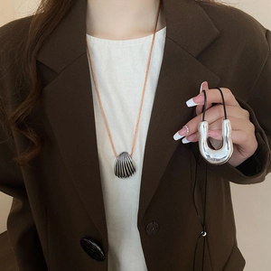 Detailed close-up of silver shell and U-shaped pendants with orange and black cords