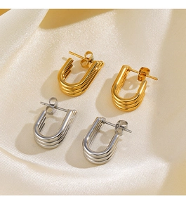 Detailed view of U-shaped multi-layered gold and silver earrings on silk background