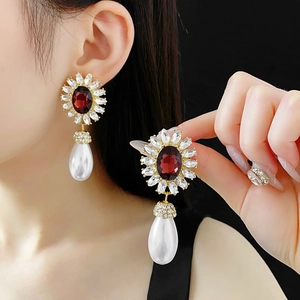 Detail of vintage gold flower earrings with red gemstone and teardrop pearl drops