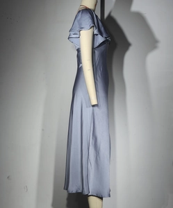 Détail d'une robe longue en satin avec col en V, manches volantées et tissu brillant lisse