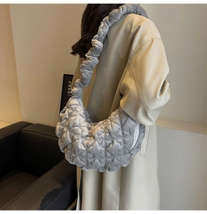 Close-up of gray quilted velvet cloud bag with pleated strap shown on a model