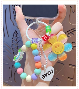 Close-up of a rainbow beaded strap with a smiley flower and LOVE heart pendant