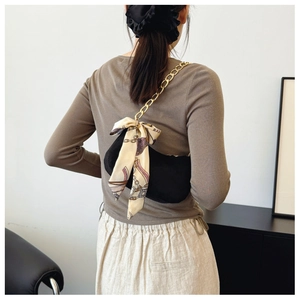 Detail of black matte shoulder bag with gold chunky chain and decorative silk scarf bow