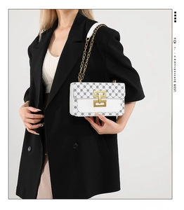 Gros plan sur sac bandoulière en cuir blanc avec motif floral et boucle en métal doré