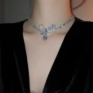 Close-up of a silver bow necklace with a pear-shaped zircon drop pendant worn by a model