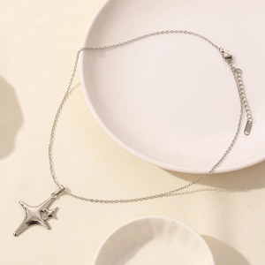 Detail of silver star pendant necklace on ceramic plate with S.STEEL material engraving